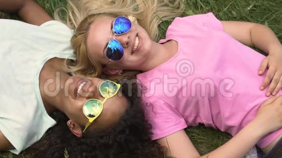 年轻女性在草坪上放松享受周末最好的朋友出去玩视频的预览图
