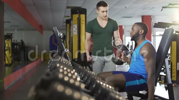在健身房锻炼哑铃时一个支持性的年轻人激励朋友健身视频的预览图