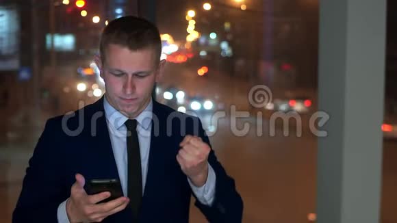 这个人是个商人看着智能手机愤怒试图控制愤怒视频的预览图