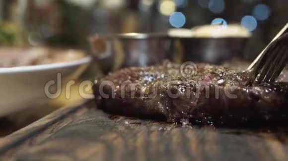 用刀子切在木板上的热汁牛排在特写镜头中中熟度牛排视频的预览图