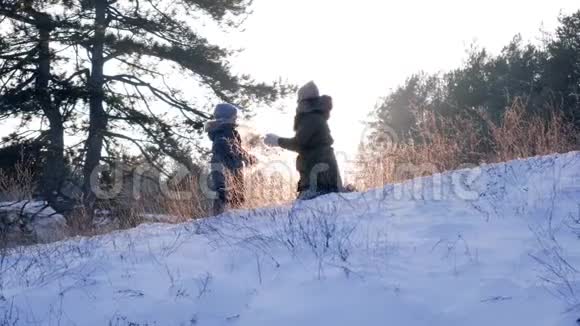 快乐的冬歇妈妈和儿子在雪地里玩背光游戏背景是美丽的大自然视频的预览图