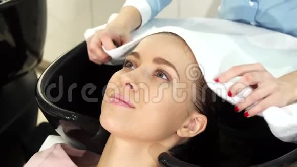 一位年轻漂亮的女士用一个专业的理发师把湿发裹在毛巾里视频的预览图