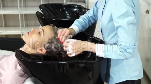 迷人的年轻女理发师微笑着对着在她的沙龙工作的相机视频的预览图