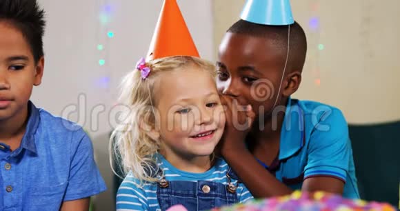 在生日聚会上男孩和朋友坐在一起时对女孩低声说话视频的预览图
