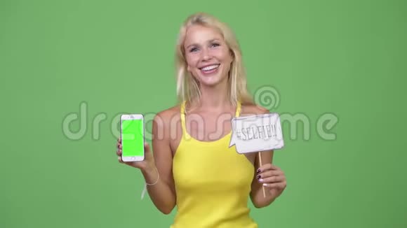 年轻快乐的金发女郎带着纸签的手机视频的预览图