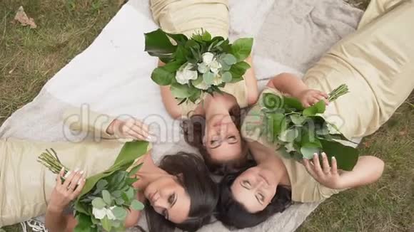 在三位美丽的微笑伴娘的黄金裙上谈论和触摸白色的婚礼花束视频的预览图