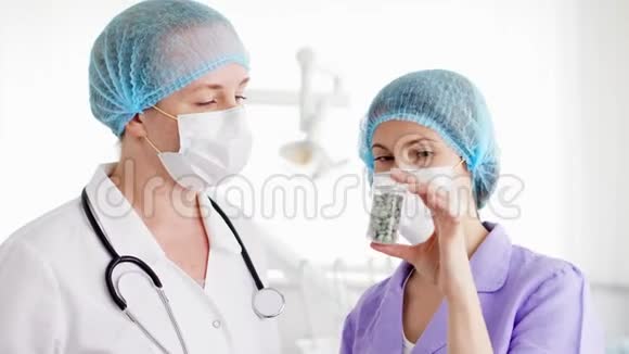 两名戴着医用口罩的女医生在医院讨论新的治疗方法一瓶药丸视频的预览图