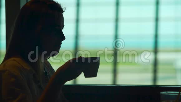 年轻女士坐在机场餐厅享受热咖啡旅游视频的预览图