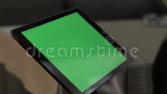 女性手触摸绿屏平板电脑坐在咖啡桌上视频的预览图
