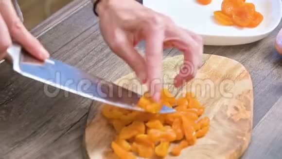 用刀在切割板上切割杏干的雌手烹饪素食视频的预览图