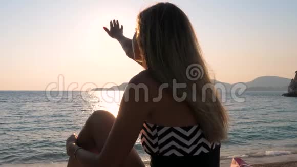 女人的手在沙滩上的天空中捕捉太阳视频的预览图