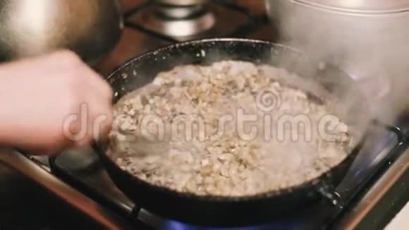 女人在铸铁厨房的煎锅上用洋葱炒蘑菇视频的预览图