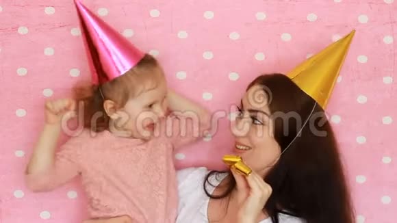 生日快乐戴着节日帽子的女人和孩子吹角笑着笑着妈妈和女儿玩得开心视频的预览图