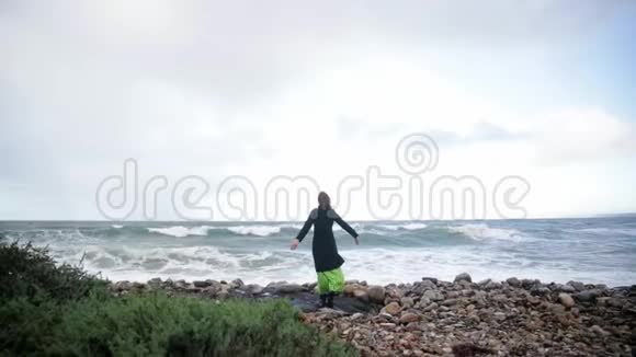 动机射击幸福女人的后景在天空中举起双手看着海滩上的海洋寒冷视频的预览图