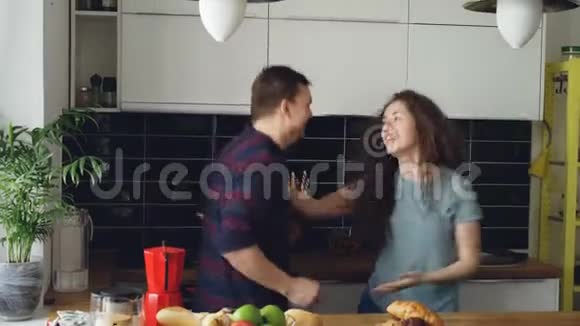 疯狂的恋爱中的年轻夫妇在假日的厨房里一起跳摇滚舞视频的预览图