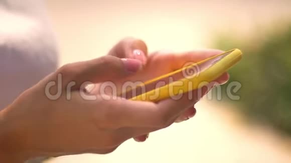 夏季阳光明媚的一天女性在智能手机上输入信息的手交流观念模糊的背景侧视视频的预览图