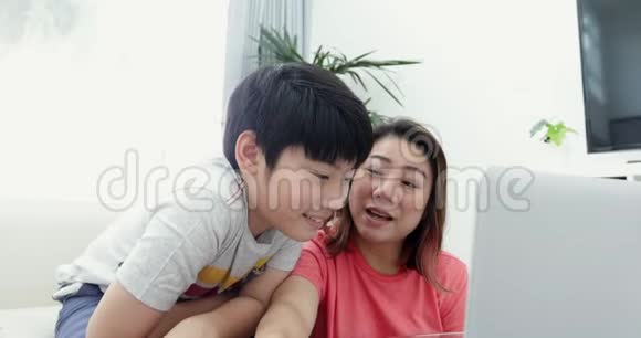 年轻的亚洲母亲和他的儿子微笑着在笔记本电脑上工作视频的预览图