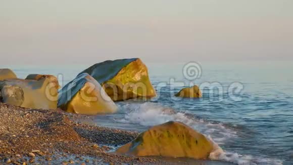 夏天晚上海浪冲刷海滩上的大石头视频的预览图