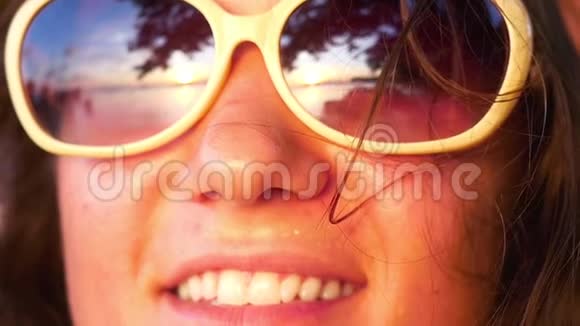 年轻快乐的女人戴着太阳镜缓慢地看着夕阳1920x1080视频的预览图