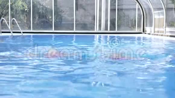 两个穿着粉红色泳衣的双胞胎金发女郎在蓝色的水池里游泳视频的预览图