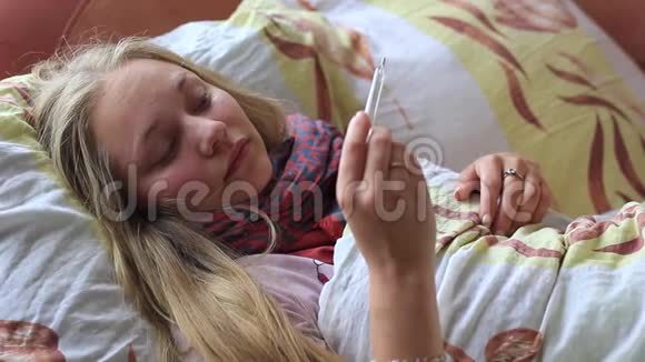 生病的女孩躺在床上测量体温视频的预览图