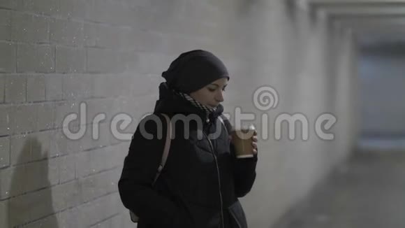 漂亮的女人在隧道里喝热咖啡等人拖延冬天视频的预览图