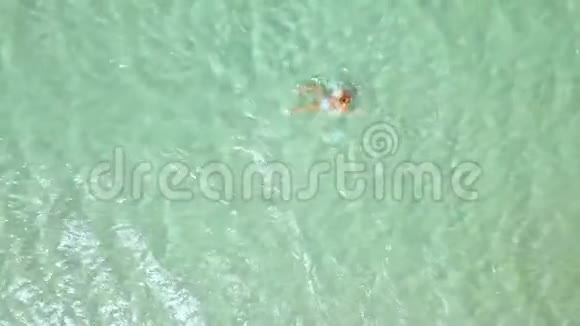 俯视的女人在清澈的海水中游泳女人在天堂海滩的绿松石海水中洗澡顶部视图视频的预览图