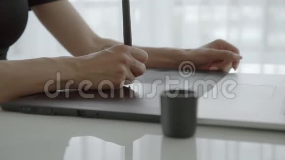 女性手使用图形平板电脑在桌子上关闭在家拿着笔记本电脑工作的女人视频的预览图