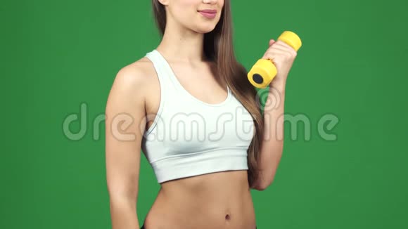 一个快乐的女运动员用哑铃举着一瓶水视频的预览图