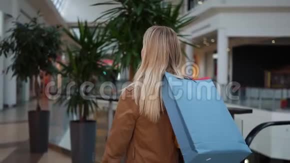 从后面看一个漂亮的女人拿着购物袋在商场里走来走去视频的预览图