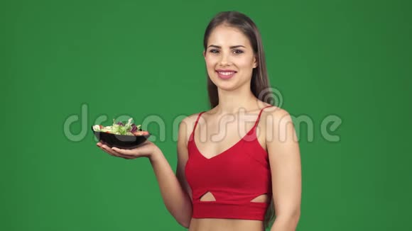 年轻健康的快乐女人微笑着拿着一碗新鲜沙拉视频的预览图