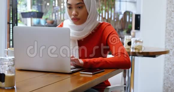 女人一边喝咖啡一边用笔记本电脑和手机4k视频的预览图