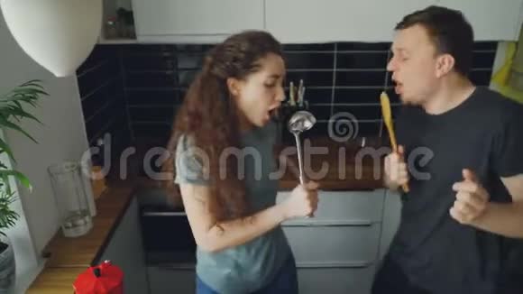年轻快乐的一对夫妇在节日的时候在厨房里做饭一边跳舞一边唱歌视频的预览图