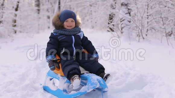 冬天快乐的笑男孩坐在雪橇上视频的预览图