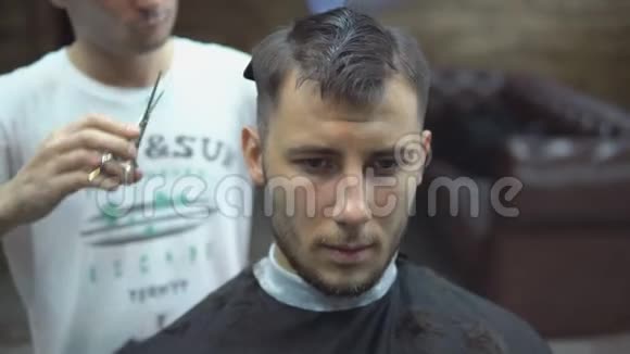 特写大师在理发店给男人剪头发和胡须理发师给年轻人做发型视频的预览图