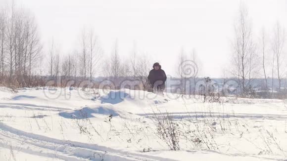 穿着冬装的成年男子骑着小雪车在雪地里快速跳跃视频的预览图