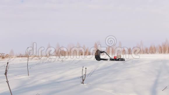 穿着冬装的人在雪地里的雪地里骑着迷你雪车行走视频的预览图