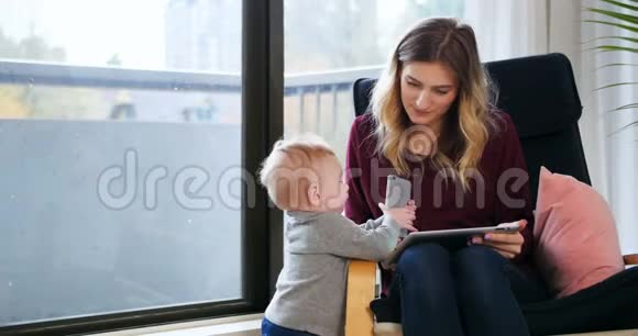 母亲在照顾婴儿时使用数码平板电脑视频的预览图