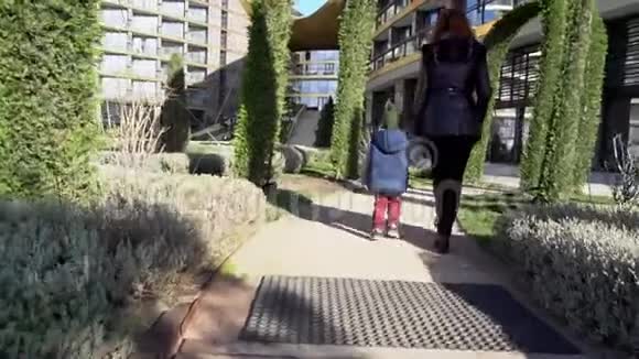 母亲和小儿子走过街上的公园视频的预览图