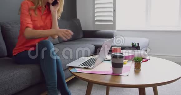 女性高管在现代办公室使用笔记本电脑时使用手机聊天视频的预览图