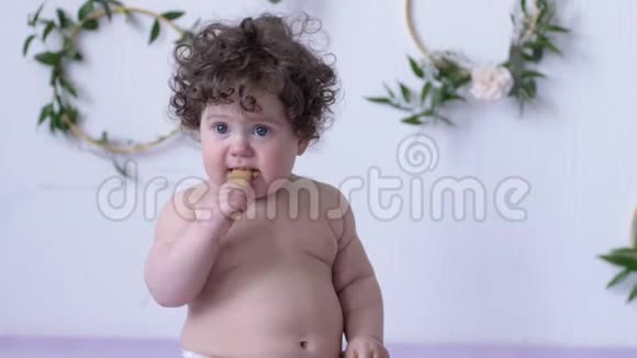 有趣的婴儿在白墙背景的摄影棚里吃饼干视频的预览图
