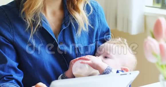 母亲在给婴儿喂4k奶的同时使用数字平板电脑视频的预览图