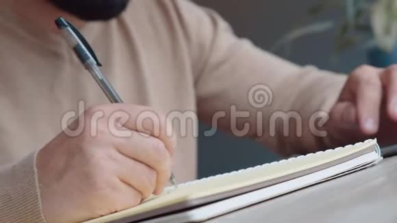 穿浅色毛衣的人用黑色钢笔在笔记本上写字特写视频的预览图