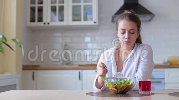 一个女人在美丽的晨光中拿着一盘新鲜的绿色沙拉她拿着叉子视频的预览图