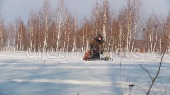 穿着冬装的成年男子在雪地里的小型雪车拖车里载着乘客视频的预览图