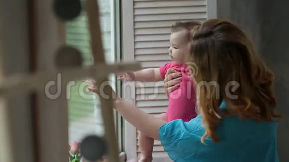 快乐的妈妈宝贝女儿透过窗户视频的预览图
