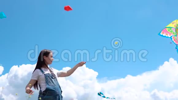 一年轻怀孕女孩连衣裙发射风筝对抗蓝色天空云彩视频的预览图