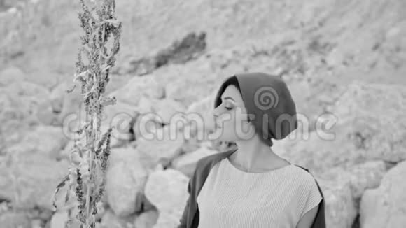 一个年轻的女人站在山和石头的背景下有着神奇的草女巫黑白图像视频的预览图