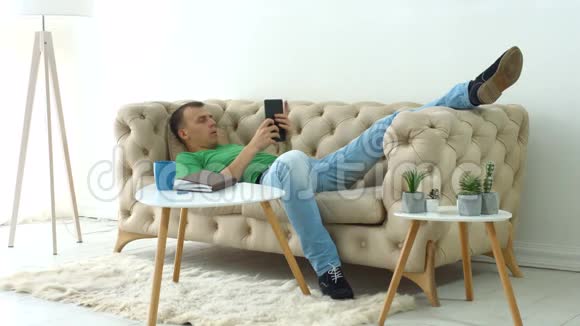轻松的男人在家里玩数字平板电脑视频的预览图