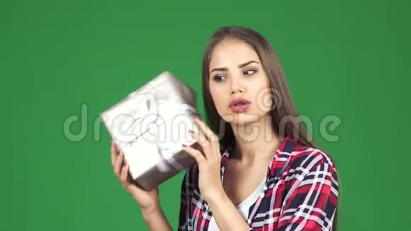 令人惊讶的快乐年轻女子摇着礼物盒猜测里面是什么视频的预览图